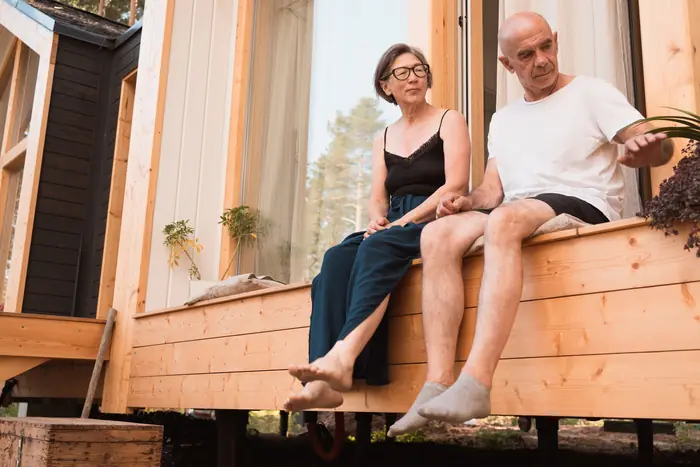An older couple sitting together on their front porch