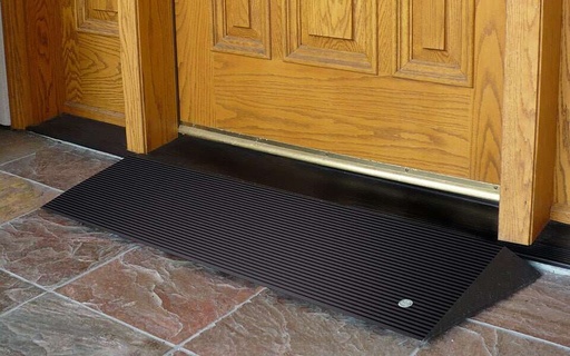 Angled entry mat at a wooden front door with a brass kick plate