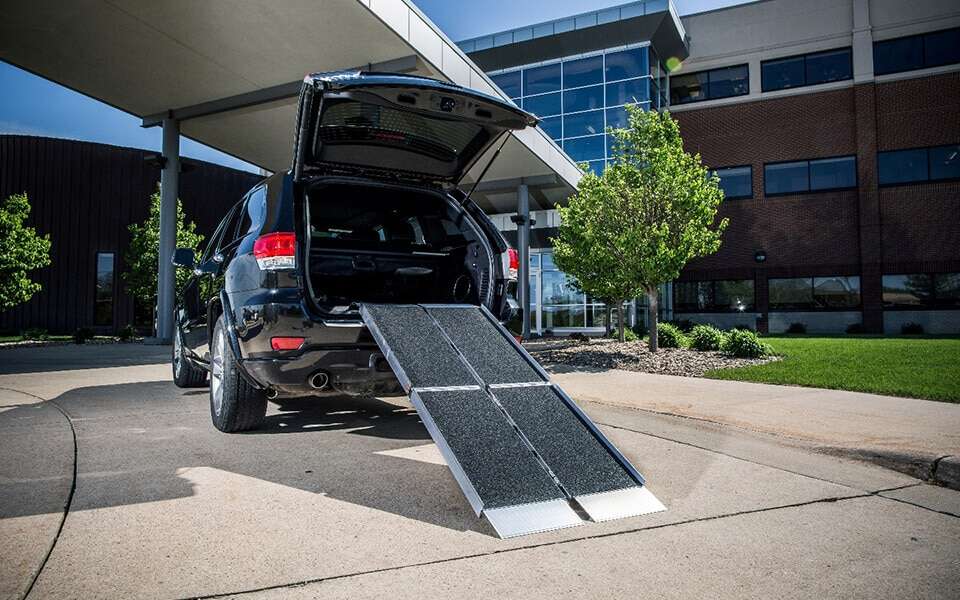Black SUV at a building with the trifold ramp set up at its rear hatch