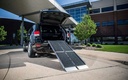 Black SUV at a building with the trifold ramp set up at its rear hatch