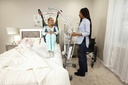 A person lifted clear of a bed in a sling on the Carina 350, with a wheelchair behind