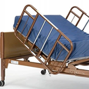 Full-length brown side rail and blue mattress fitted to the raised head section