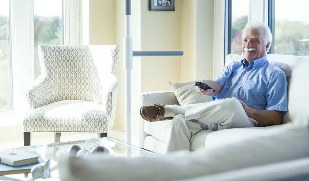 Man resting on a sofa, with the pole and its bar standing at the end of the sofa within reach