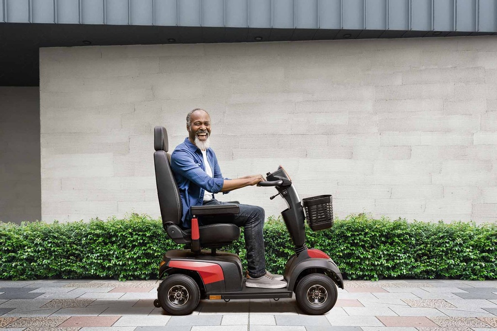 Side view of a rider on the red Comet Pro on a sidewalk, showing its length and seat height