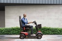 Side view of a rider on the red Comet Pro on a sidewalk, showing its length and seat height