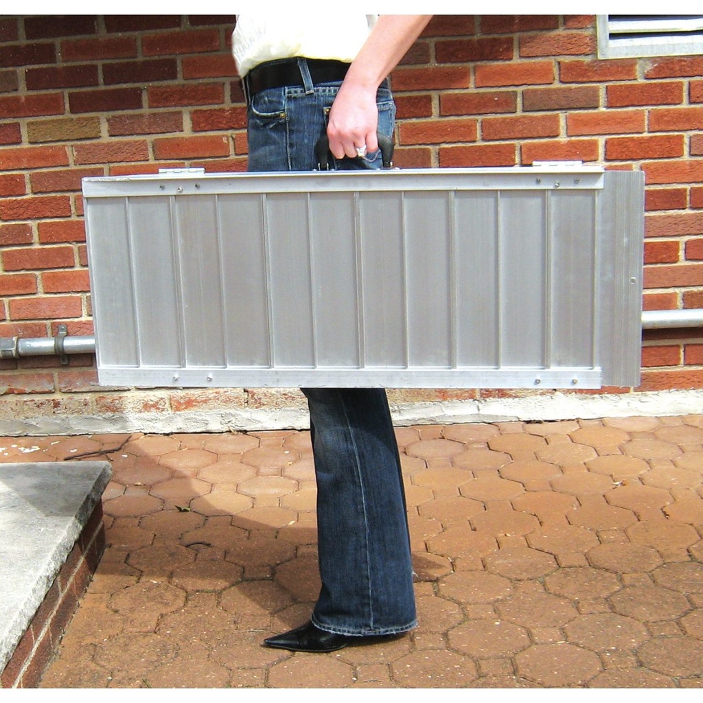Person carrying the folded single-fold ramp by its built-in handle outdoors