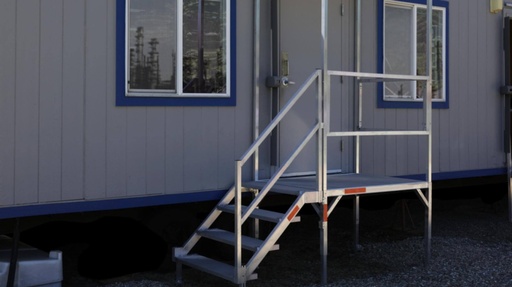 Four-riser aluminium stair installed at the door of a grey modular building