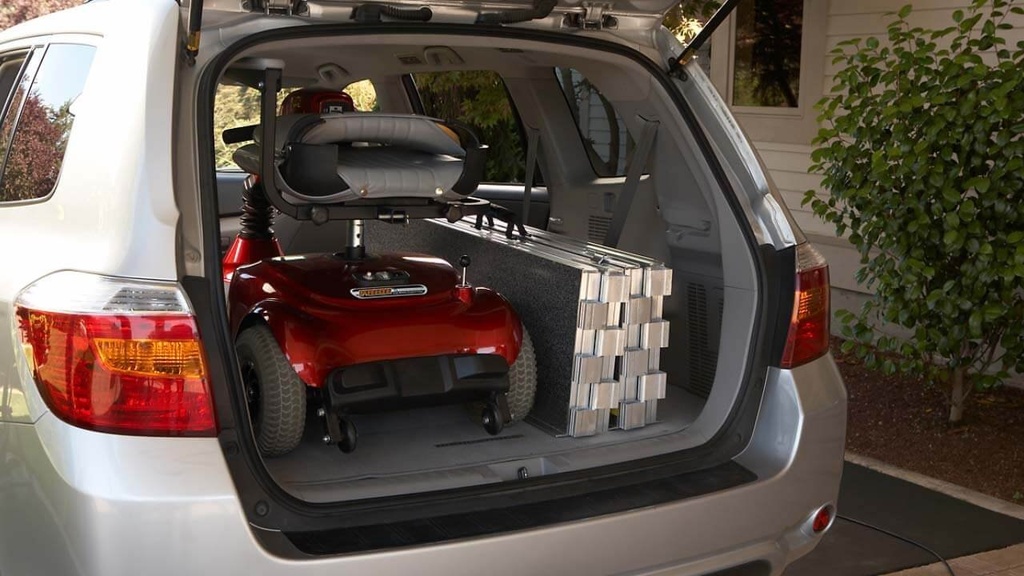 Ramp folded flat on edge beside a scooter in an SUV cargo area