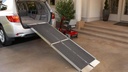 Red mobility scooter beside a silver SUV with the trifold ramp in place
