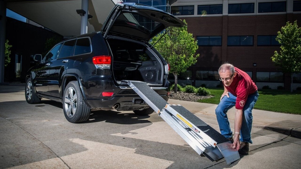 Man setting the bottom transition plate of the trifold ramp at an SUV