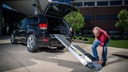 Man setting the bottom transition plate of the trifold ramp at an SUV