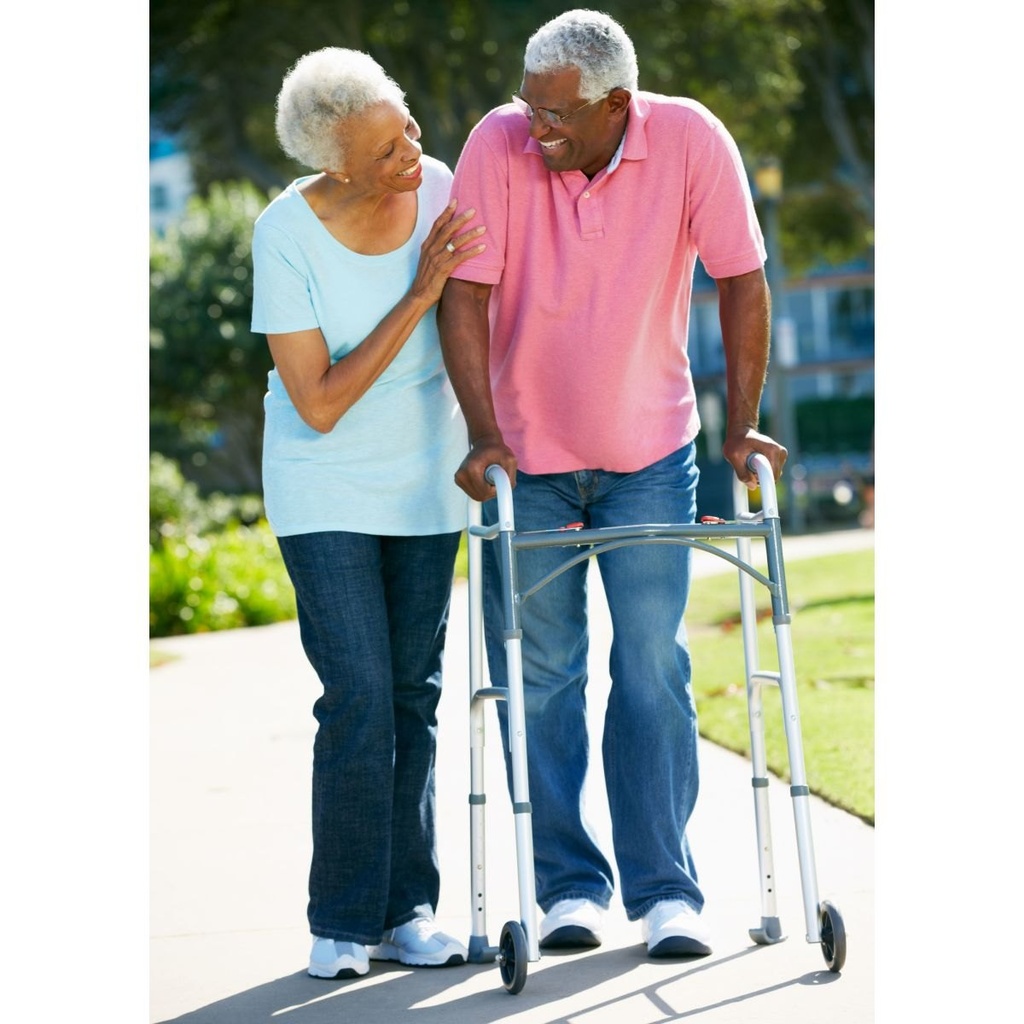 An older adult walking with the Drive two-button folding walker on an outdoor paved path