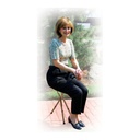 A person seated on the open cane seat outdoors, resting with the folded frame under the seat