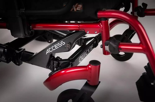 Close view of the red and black rigid frame, caster and axle plate on a Quickie Access wheelchair