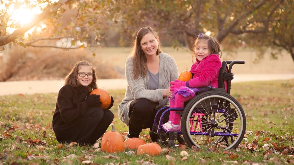 Child seated in a purple ZIPPIE X'CAPE outdoors with two family members