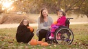 Child seated in a purple ZIPPIE X'CAPE outdoors with two family members