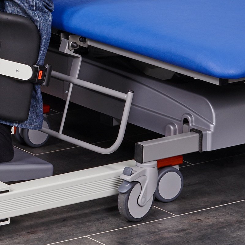 Floor lift chassis under the MONA care and treatment table, showing the clearance beneath