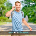 Man walking outdoors wearing a Tynor Posture Corrector over a blue T-shirt