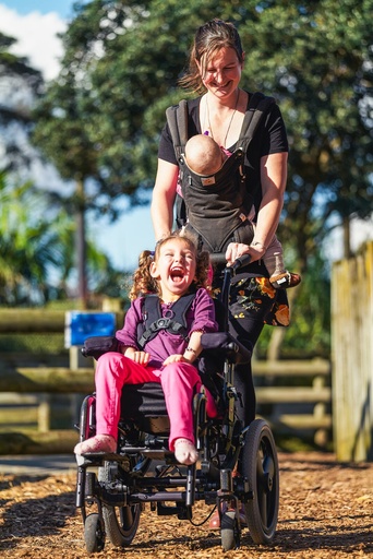 A child seated in the Spex Wonderseat on a wheelchair outdoors