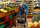 Person putting produce into the basket of a two-wheel walker