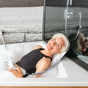 A bather reclined on the Bellavita Dive lift holding the floating hand control