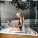 A person seated upright on the Bellavita Dive lift in a bathtub