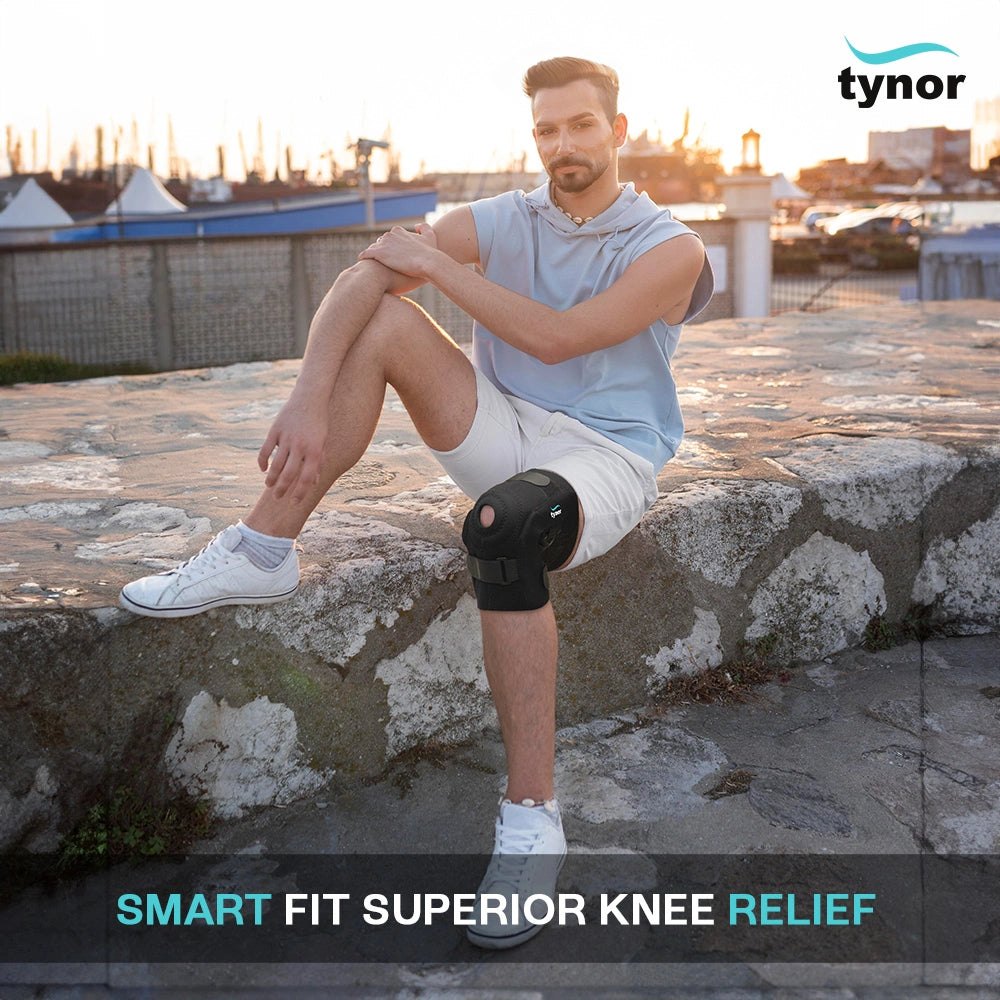 Man sitting cross-legged on a stone wall wearing a Tynor Hinged Knee Wrap