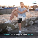 Man sitting cross-legged on a stone wall wearing a Tynor Hinged Knee Wrap