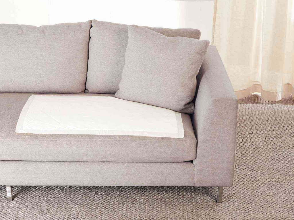 A Depend Night Defense underpad laid on a sofa cushion