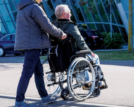 Empulse R20 Assist for Caregivers. Caregiver pushing a manual wheelchair with the R20 drive wheel under the frame