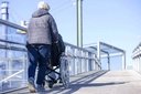 Caregiver pushing the chair along a pedestrian bridge, R20 backpack on the back