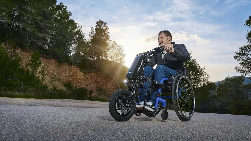 Rider steering a StreetJet handbike on a paved road, with the front wheel leading