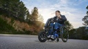 Rider steering a StreetJet handbike on a paved road, with the front wheel leading