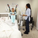 Caregiver moving a person beside a bed with the Carina 350 floor lift and hand control