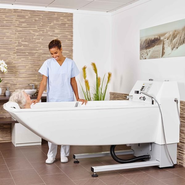 A carer washing a resident lying in the Beka Avero Premium Plus care bathtub