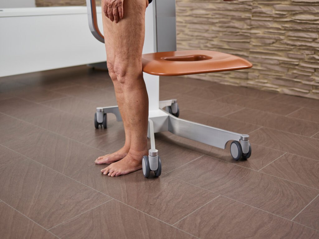 The Eve lift seat at its lowest with a resident standing beside it, showing the low step-on height