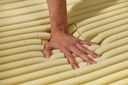 Close view of yellow foam tubes, a hand pressing the mattress surface.
