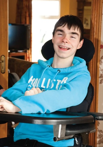 A boy seated in the Leckey Everyday Activity Seat at the tray