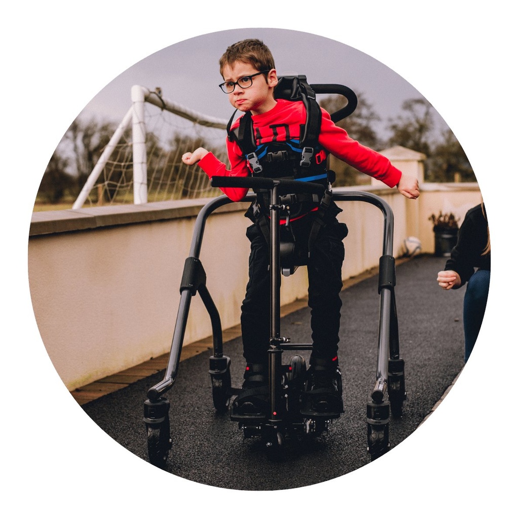 Child walking in the MyWay Plus gait trainer on an outdoor path, with the whole frame in view