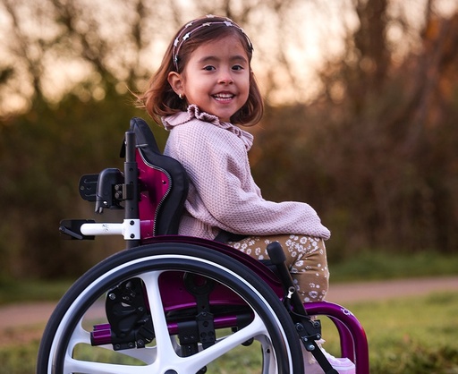 A child seated in a wheelchair fitted with an Axiom for Kids back support