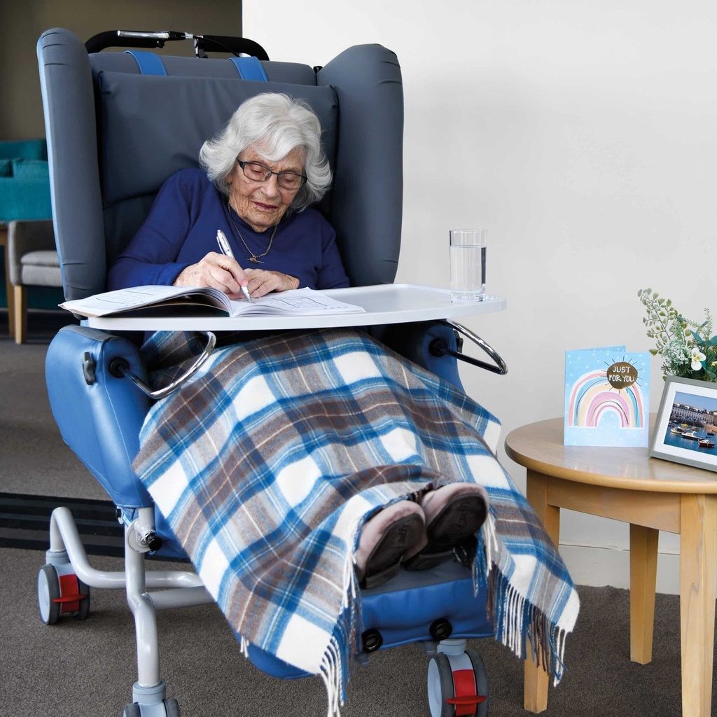 Person seated in the K-Care Air Comfort Chair with a lap tray