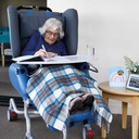 Person seated in the K-Care Air Comfort Chair with a lap tray