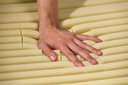 Hand pressing the yellow foam cells of a convoluted overlay