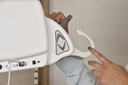 A hand sliding a sling loop into the SureClip hook on the portable lift