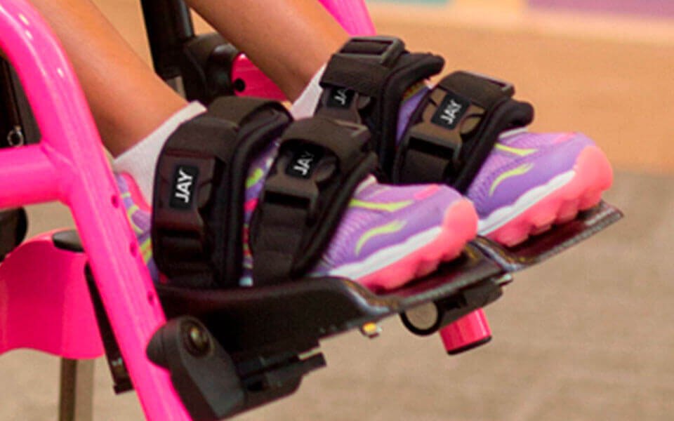 JAY shoe holders strapped over a child's shoes on wheelchair footplates