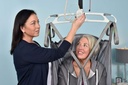 Carer holding the FL lift hand control while a person sits in a sling below the carry bar