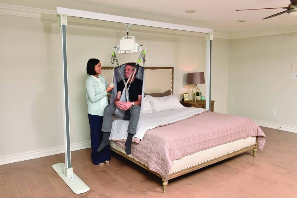 Monarch portable ceiling lift hanging from the Savaria Gantry beside a bed