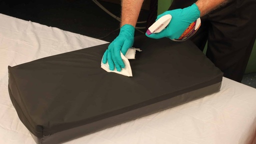 Gloved hand wiping the black cover of the Span Heel Manager on a bed