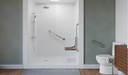 Knurled bars on a walk-in shower wall and beside a toilet