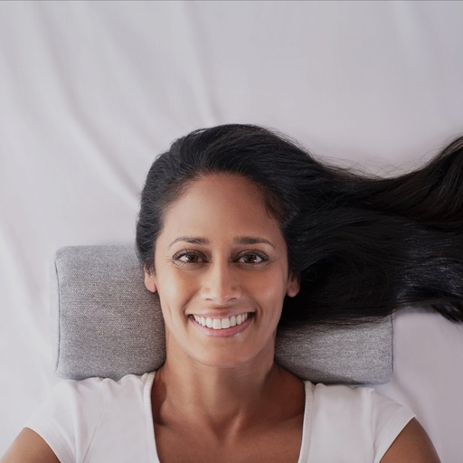 Grey half-moon pillow under the neck, on a white bed